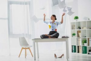 Save time build a stop list woman sitting on desk throwing papers into the air to show stopping tasks